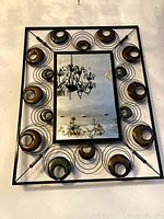 Full view of the modern metal framed wall mirror showing decorative circular metal rings with wooden accents in the frame surrounding the rectangular mirror surface.