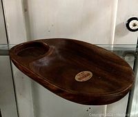 Photo of a single vintage teak wooden dish showing the oval shape with an integrated circular dip for holding items.