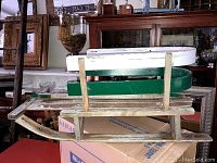 Side view of the vintage child's wood sled showing wooden slats, metal runners and the pushing handle