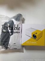 Packaged portable projection screen and boxed LED projector with yellow and white design