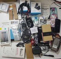 Overview of the lot showing grouped items including wireless chargers, cables, cases, and accessories on table.