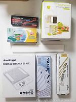 Top view of all boxed items including food spiralizer, digital thermometer, can opener, kitchen scale, and packaged flatware.