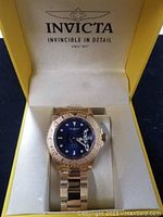 Invicta men's Pro Diver watch displayed inside open yellow Invicta box showing watch face and strap.