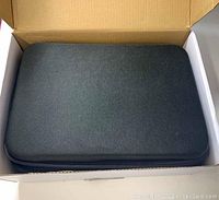 Closed black hard carrying case inside a cardboard box.