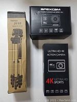 Photo of the boxed Apexcam M80 Air camera, Ultra HD 4K Action Camera box, and tripod box.