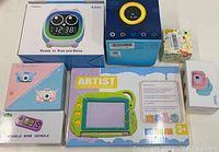 Photo showing all items in their boxes including IToma Addo owl clock, handheld game console, digital cameras, smart watch, and drawing board