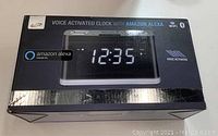 Box front showing image and product title indicating voice activated clock with Amazon Alexa.