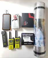Group photo of camping lot items including walkie talkies, EVA mat, power bank, weather radio, headlamp, and bait casting reel boxed.