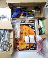 Overview of all tools and accessories including saw blade in packaging, glue gun, clamps, and attachments