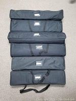 Six black carrying cases arranged on floor with handles and straps visible.
