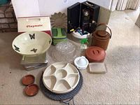 Photo showing large plastic chip bowl with butterfly motif, vintage faux leather ice bucket, tortilla keeper, cake carriers, chip and dip containers, and Playmate cooler in the background.