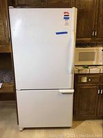 Front view of the white Kenmore Sears refrigerator with freezer below, showing the full height appliance standing in a kitchen setting.