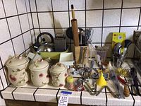 Whole lot showing ceramic canisters, tea kettle, vintage electric hand mixer with beaters, rolling pin, metal grater and assorted kitchen utensils and gadgets.