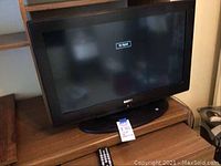 Front view of Sanyo LCD TV on wooden cabinet, screen showing 'No Signal'.