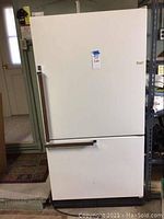 Front view of Kenmore white refrigerator with bottom freezer compartment, shows unit with closed doors and metal handles.