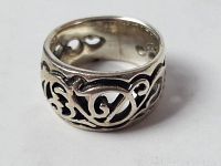 Close-up photo of vintage silver ring showing scrollwork design and band width.