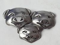 Front view showing three silver-toned pig face brooch pins with distinct expressions.