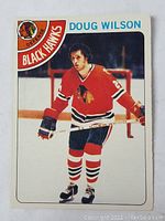 Front image of Doug Wilson rookie hockey card in Chicago Black Hawks uniform on ice.