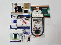 Five hockey trading cards featuring game-used jersey patches arranged on white surface