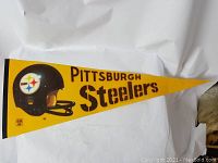 Full view of the yellow triangular vintage pennant with Pittsburgh Steelers text and helmet graphic