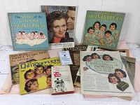 Photo showing the assortment of Dionne quintuplets ephemera including magazines, booklets, and advertisements arranged on a white surface.