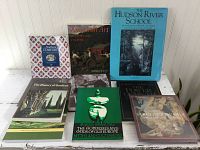 Photo showing the front covers of eight books arranged standing and lying down, titles visible including The Hudson River School, American Art, Northern Comfort, The History of Gardens, Maria Gimbutas, and Sargent's America.