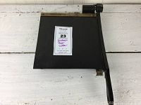 Top-down view of Eastman paper cutter showing full cutting surface and arm with label showing lot details.