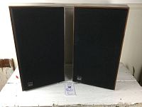 Front view of both speakers with grills attached side by side on a white surface.