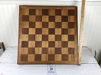 Full view of handmade wooden chessboard with ruler for scale, showing square checker pattern and wooden border.