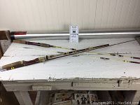 Two fiberglass fishing rods laid out on table along with the aluminum rod case.