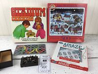 Four puzzle and game boxes including Stadium Checkers, Jane Wooster Scott 500-piece puzzle, Amaze maze puzzle, and a crystal radio with tuning knobs and switches.
