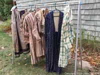 Five costumes hung on rack outdoors, overall view