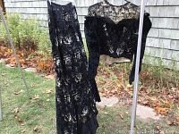 Full view of the black floral lace and velvet skirt with matching top hanging outside on a rack.