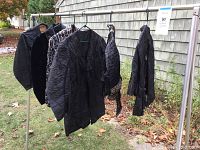Six antique jackets hanging outdoors showing varied decorations and dark colors