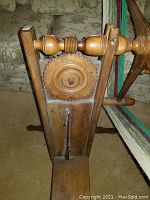 Close-up of wooden turning gear and foot pedal mechanism showing age and wood detail.