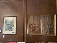 Two framed prints hanging on the wall, one landscape and one indoor scene with people, both with gold frames.