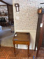 Front view of antique wooden slant front desk positioned against a wall, showing top surface and ink well.