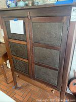 Front view showing two doors with punched tin panels and top surface