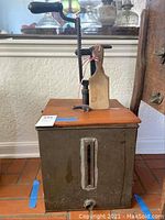 Full view of antique butter churn showing metal base, wooden lid, hand crank and wooden paddles.