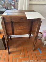 Front view of entire wooden butter churn on stand showing barrel and legs