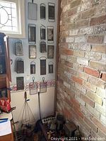 Photo showing multiple metal food graters mounted on a wall and several kitchen tools below against a brick wall.