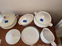Wide view of all items on table showing the variety of ceramic dishes including casserole dishes, covered bowl, gravy boat, and plates