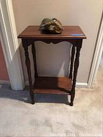Front view of dark wood side table with the stone head sculpture on top