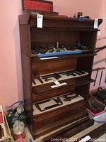 Full front view of three-tier bookcase showing glass-front sections and bottom drawer