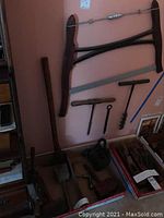 Overview of the vintage woodwright tool set, showing the full collection including the wooden frame clamp, frame saw, hand drills, iron weight, nail, and additional wooden tools laid out for inspection.