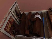 Photo showing wooden woodworking planes stacked along a corner with three woodworking books titled 'Fine Homebuilding'.