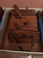 Eight wood-bodied hand planes with iron blades arranged in a box