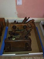 Overview of both wooden plow planes resting in a shallow box, showing body shape and fence assemblies