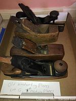 Top view showing four vintage woodworking planes with wood and metal parts in a box.