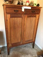 Front view of closed cupboard showing two drawers, beadboard doors and legs